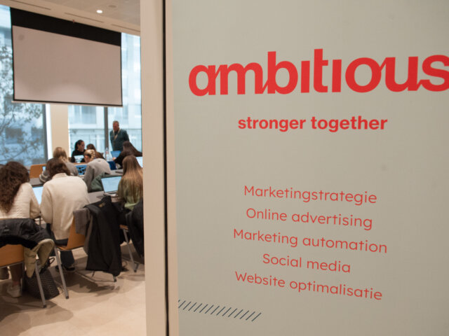 Sfeerbeeld met de Ambitious banner en werkende studenten op de achtergrond